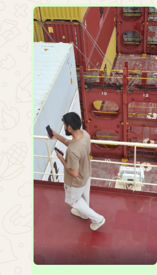 An off-duty seafarer walking along a container ship's deck holding a phone and a tablet up, searching for mobile signal
